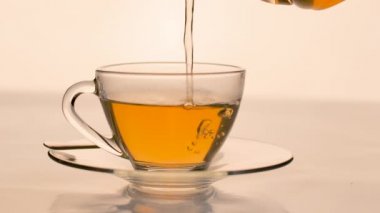 Yavaş çekim. Yakın plan çay masanın üzerindeki temiz bardağa dökülüyor..