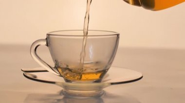 Yavaş çekim. Yakın plan çay masanın üzerindeki temiz bardağa dökülüyor..
