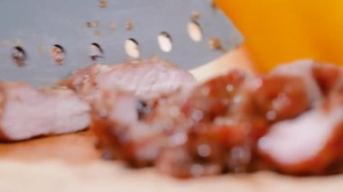 Mutfaktaki ahşap kesme tahtasının üstünde ızgara domuz dilimlemek için bıçak kullan..