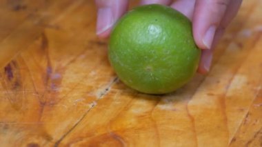 Mutfaktaki kesme tahtasındaki yeşil limonu ikiye bölmek..