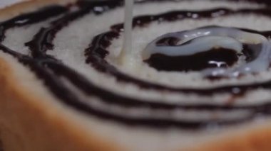 Bir dilim ekmeğin üzerine yoğunlaştırılmış süt dökülüyor.