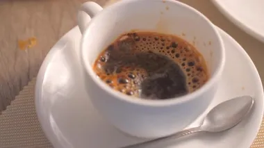 Sıcak kahveyi beyaz bir fincana doldurmak için yakın plan.