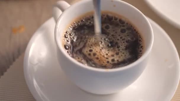 Mano Revolviendo Café Caliente Una Taza Blanca Sobre Mesa — Vídeo de stock
