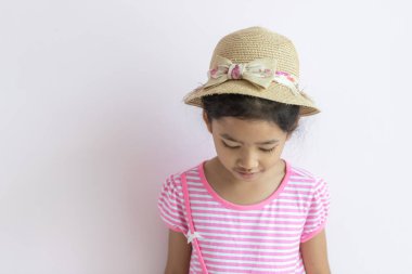 Pembe ve beyaz çizgili elbise giyen Asyalı çocukların portresi Küçük kız şapka takıyor ve aşağı bakıyor.