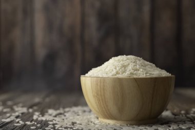 Kahverengi bir kasede pirinç, ahşap bir masada, arka planda bulanık.