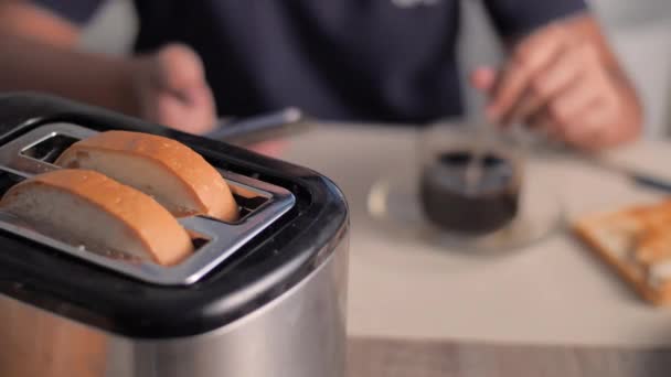 スマートフォンを使用し パンのスライスをトーストし キッチンで朝食のためのコーヒーを作る女性 — ストック動画