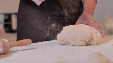 Beyaz masada hamur işi pişirmek için elini kullanan bir kadın.