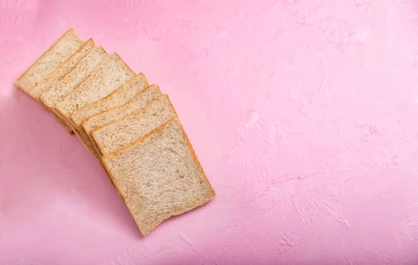 パンのスライスは色の背景に隔離されます 木のピンクの背景と食感のベーカリー — ストック写真