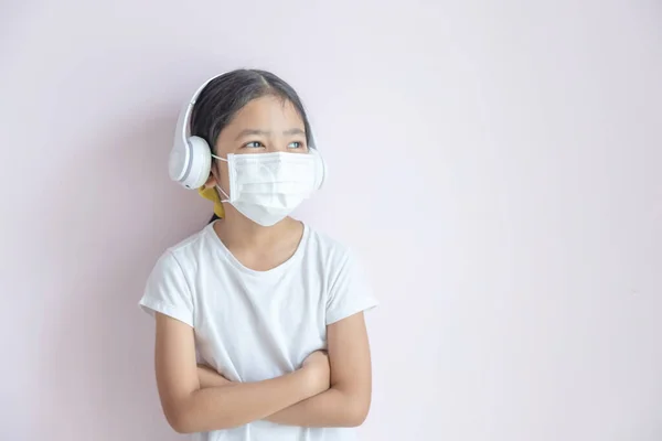 보호용 마스크와 이어폰을 아시아 소녀입니다 배경에 교차하여 있는아이 유행하는 코로나 — 스톡 사진