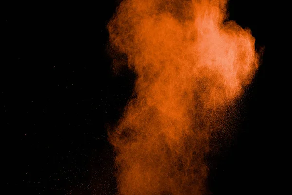 Abstract explosion of orange dust on black background. Freeze motion of orange powder burst.