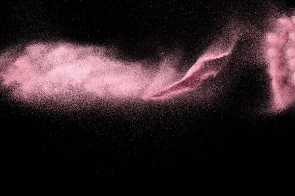 Pink dust particles splash on black background.