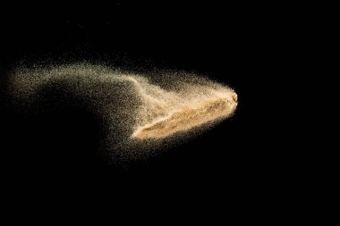 Kuru nehir kum patlaması. Kahverengi renk kum siyah arka plana sıçrar..