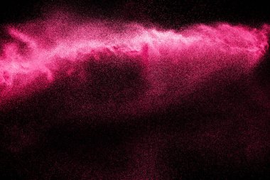 Siyah arka planda pembe toz patlaması. Pembe toz bulutu koyu arkaplanda sıçradı..