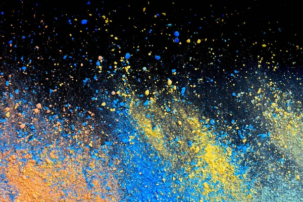 A splatter of pastel natural colored pigment powder on black background.