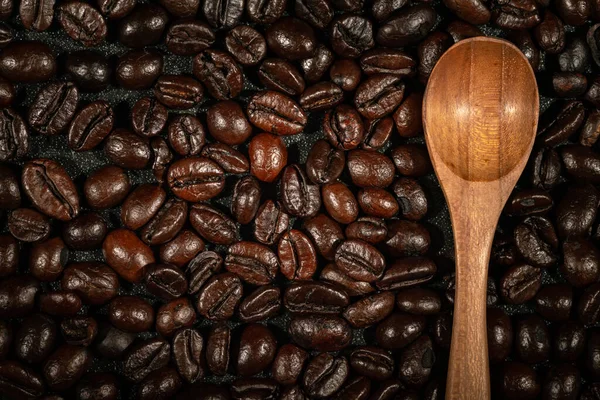 Zbliżenie Brązowych Palonych Ziaren Kawy Drewnianą Łyżeczką Tle — Zdjęcie stockowe