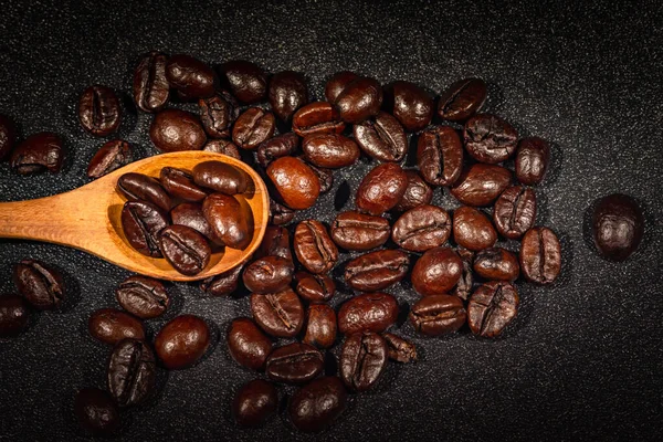Zbliżenie Brązowych Palonych Ziaren Kawy Tle Drewnianej Łyżki — Zdjęcie stockowe