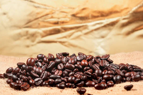 Coffee beans on brown linen fabric background.Roasted coffee beans texture, used as a background.Flat lay, top view, copy space.