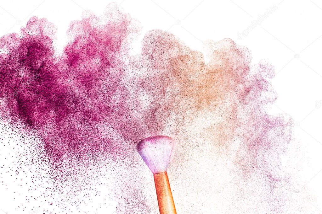 A golden brush with pink and light brown  make up powder impact to make a colorful cloud.