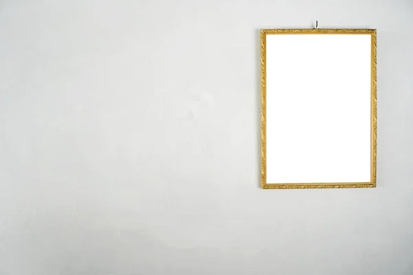 Quadro dourado pendurado em uma parede de cimento branco. — Fotografia de Stock