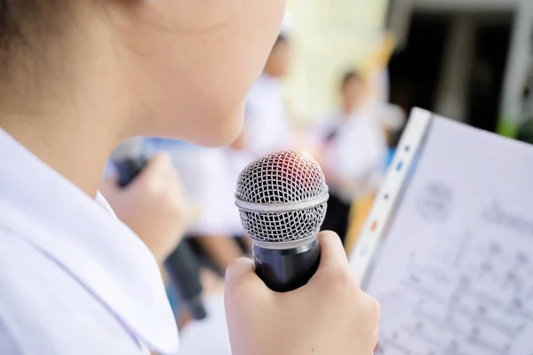 Uma menina segurando um microfone cantando uma música. — Fotografia de Stock