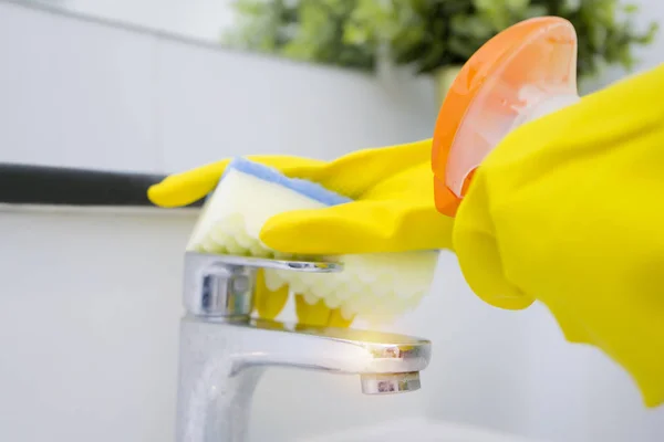 Robinet d'eau propre à l'aide de gants jaunes et éponge . — Photo