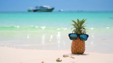 Cam ananaslar plajda, sıcak güneşin altında, deniz kenarında bulunur ve yaz için bir konsept oluşturur..