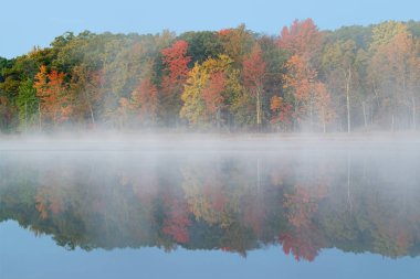 Derin Göl kıyılarının sisli sonbahar manzarası sakin sularda yansıyan yansımalarla, Yankee Springs State Park, Michigan, Usa
