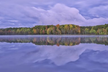 Derin Göl kıyılarının şafağında sonbahar manzarası sakin suda yansıyan yansımalarla, Yankee Springs State Park, Michigan, Usa