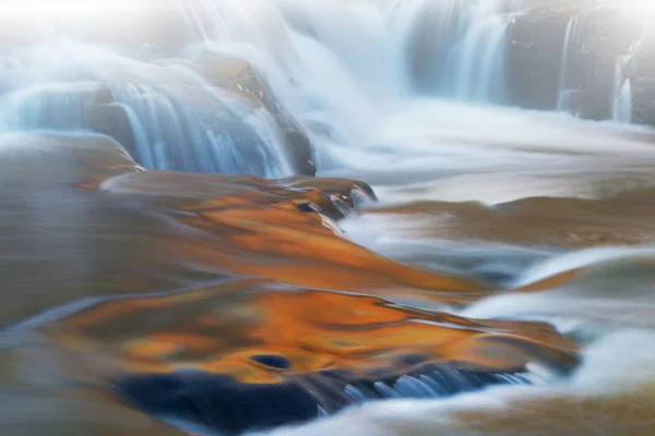 霧の中のボンド滝のカスケードの秋の風景は 動きのブレで捉えられ 太陽の光に照らされた紅葉と青空のオーバーヘッド ミシガン州のアッパー半島 アメリカからの反射色によって照らされます — ストック写真