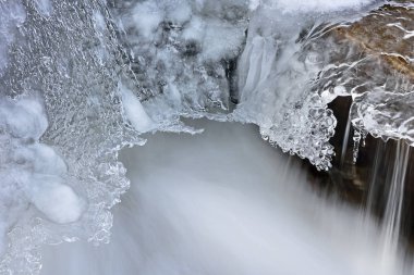 Buz sarkıtları ile çerçeveli ve hareket ile yakalanan kış Breugel Creek cascade bulanıklık, Michigan, ABD