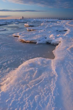 Winter, South Haven, Michigan Lighthouse with splashing wave and frozen shoreline at sunset, Lake Michigan, USA