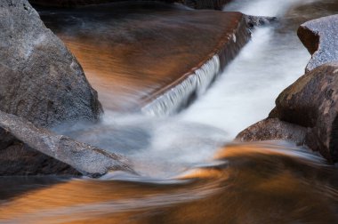 Merced Nehri 'nin manzarası hareket bulanıklığıyla kaplandı ve güneşli kayalıklardan gelen altın yansımalarla aydınlandı, Yosemite Ulusal Parkı, Kaliforniya, ABD