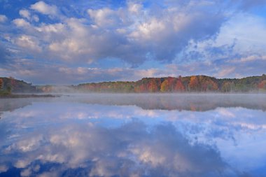 Derin Göl 'ün sisli sonbahar manzarası sakin sularda yansıyan yansımalarla, Yankee Springs State Park, Michigan, Usa