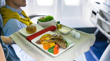 Uçuş görevlisi uçakta yemek servisi yapıyor.