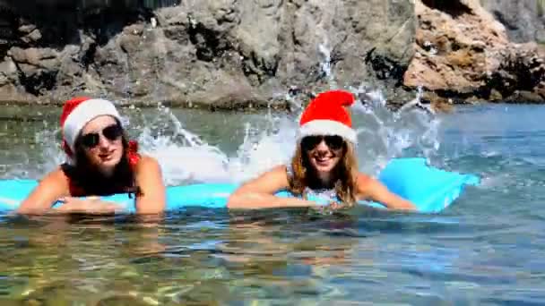 Hermosas mujeres jóvenes nadan en el mar con sombrero de Navidad — Vídeo de stock