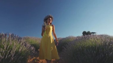Sarı elbiseli güzel bir kadın lavanta tarlasında yürüyor.