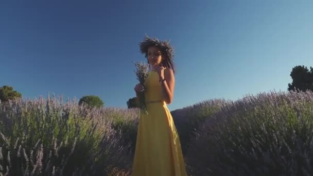 Jonge vrouw in krans met boeket staande in lavendelveld — Stockvideo