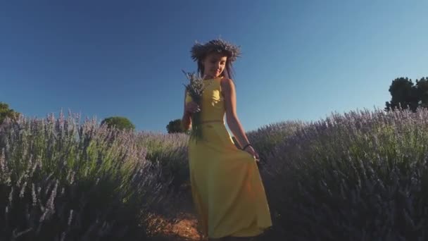 Hermosa mujer en vestido amarillo que sostiene ramo en el campo de lavanda — Vídeos de Stock