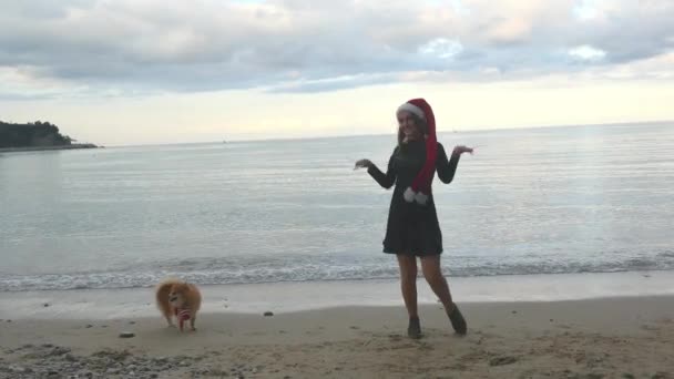 Funny woman in Santa hat funny dancing near the sea — Stock Video