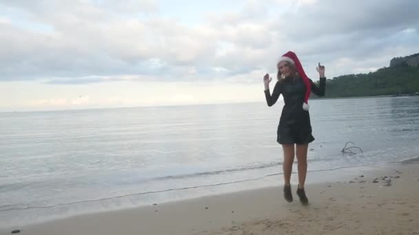 Lustige Frau mit Weihnachtsmütze lustige Tänze am Meer — Stockvideo