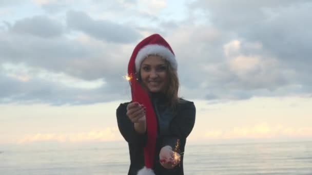 Junge Frau mit Weihnachtsmütze und Wunderkerzen in der Hand — Stockvideo