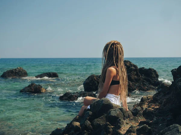 Young woman with dreadlocks sitting on the rocks — ストック写真