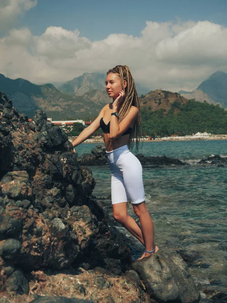 Mujer joven con rastas de pie en las rocas —  Fotos de Stock