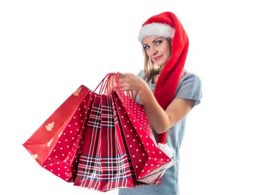 Noel Baba şapkalı genç ve güzel bir kadın. Elinde Noel çantası var.