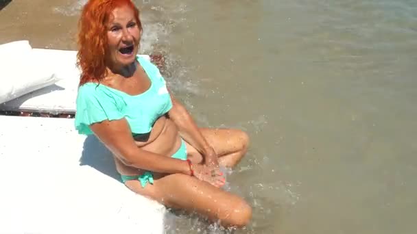 Junge alte Frau im blauen Bikini amüsiert sich am Meer — Stockvideo