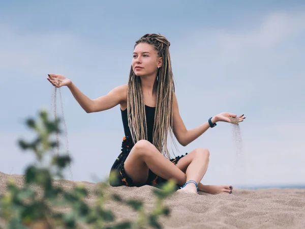 Mujer joven con rastas vertiendo arena —  Fotos de Stock