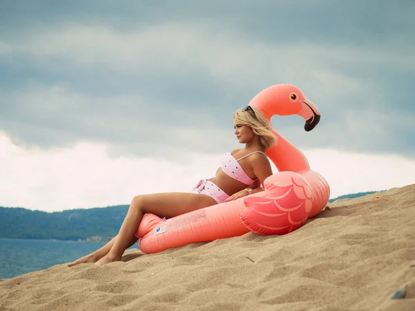 Jovem deitada no flamingo inflável na praia — Fotografia de Stock