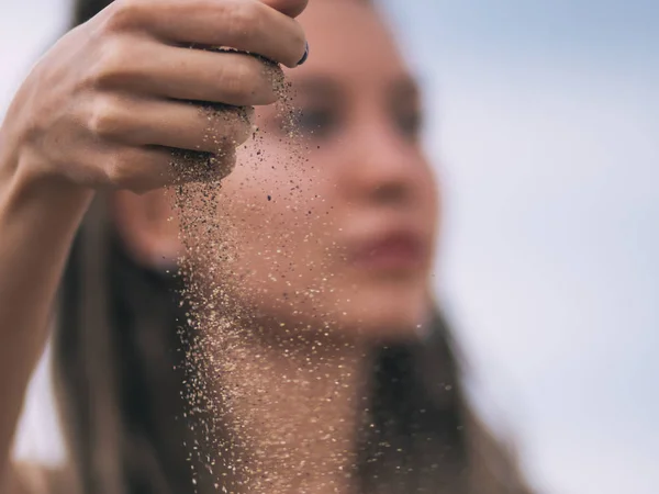 Mujer joven con rastas vertiendo arena —  Fotos de Stock