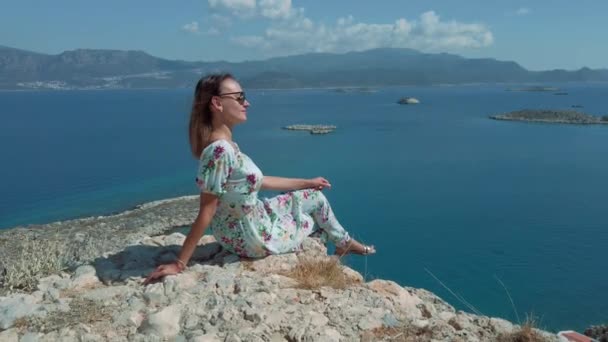 Mujer vestida sentada en el borde del acantilado sobre el mar — Vídeos de Stock