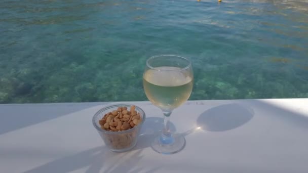 Glas Weißwein auf dem Tisch am Meer — Stockvideo